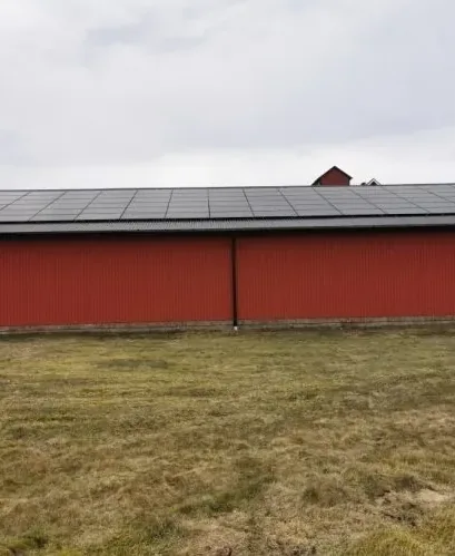 Röd ekonomibyggnad med solpaneler längs hela taknocken
